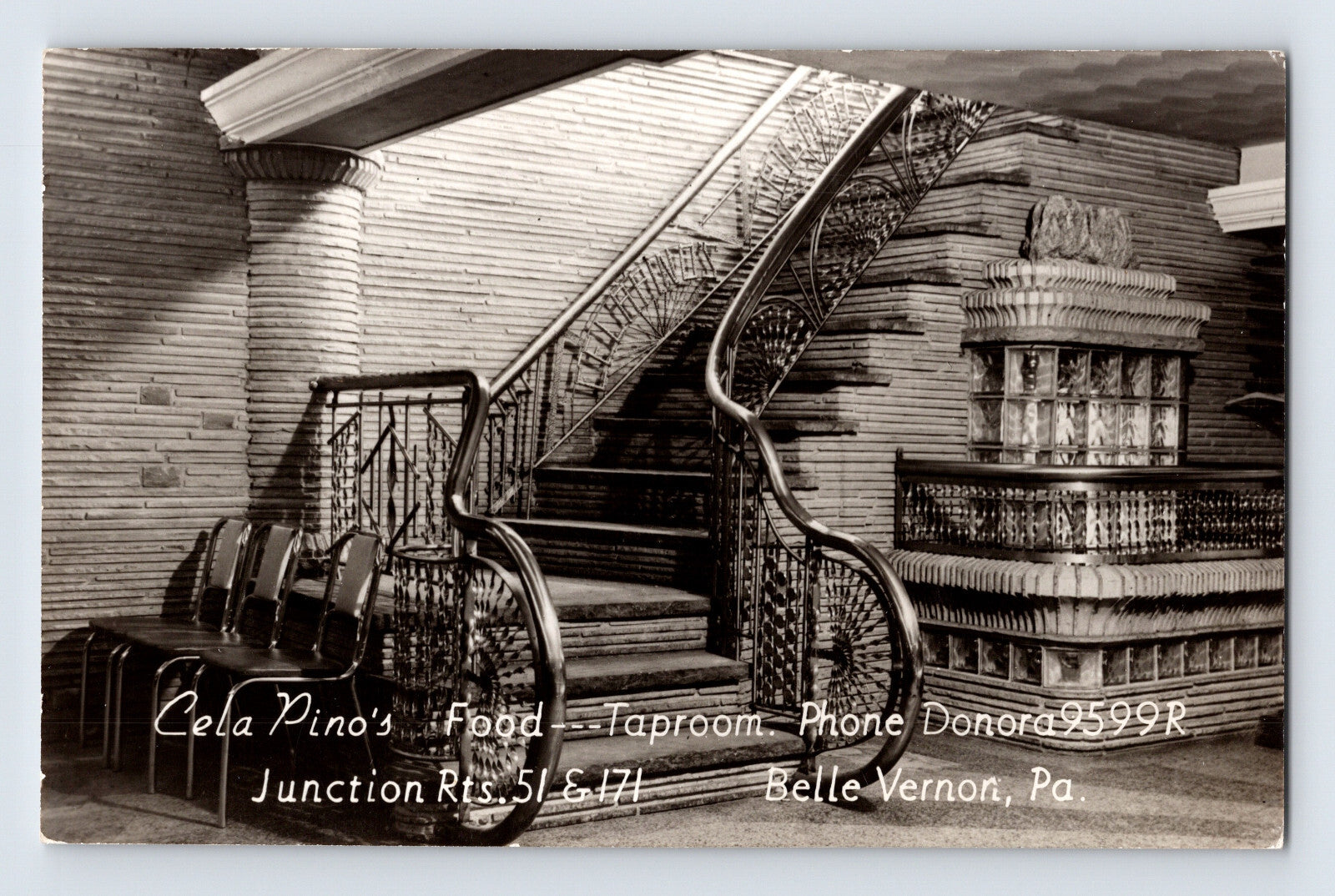 Black-and-white postcard interior view of Cela Pino’s Taproom in Belle Vernon, Pennsylvania, featuring an ornate curved staircase and decorative mid-century restaurant décor.
