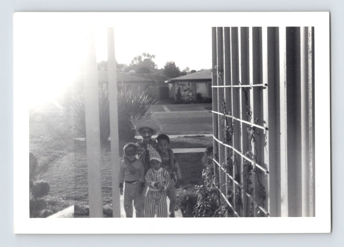 Children Halloween costumes walking sidewalk suburban neighborhood striped outfit mask 1950s black and white snapshot