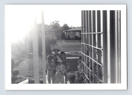 Children Halloween costumes walking sidewalk suburban neighborhood striped outfit mask 1950s black and white snapshot