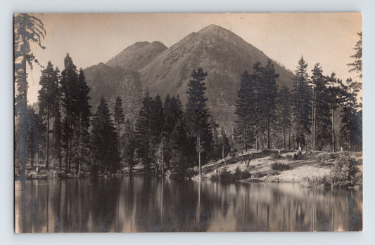 Real photo postcard showing Black Butte in California, with forested shoreline and mountain reflection across calm lake water; divided back format, unposted.