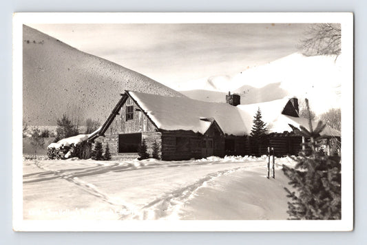 Sun Valley Idaho Trail Creek Cabin in winter snow with log lodge buildings and mountain slope background real photo postcard