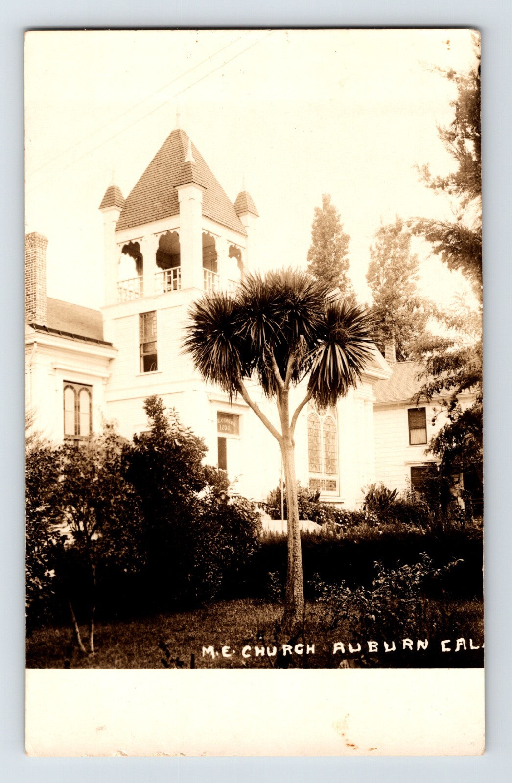 Real photo postcard of Methodist Episcopal Church Auburn California with bell tower and palm tree 1920s