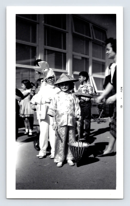 Children in costume parade schoolyard Halloween outfits rabbit and Asian costume umbrella 1960s snapshot