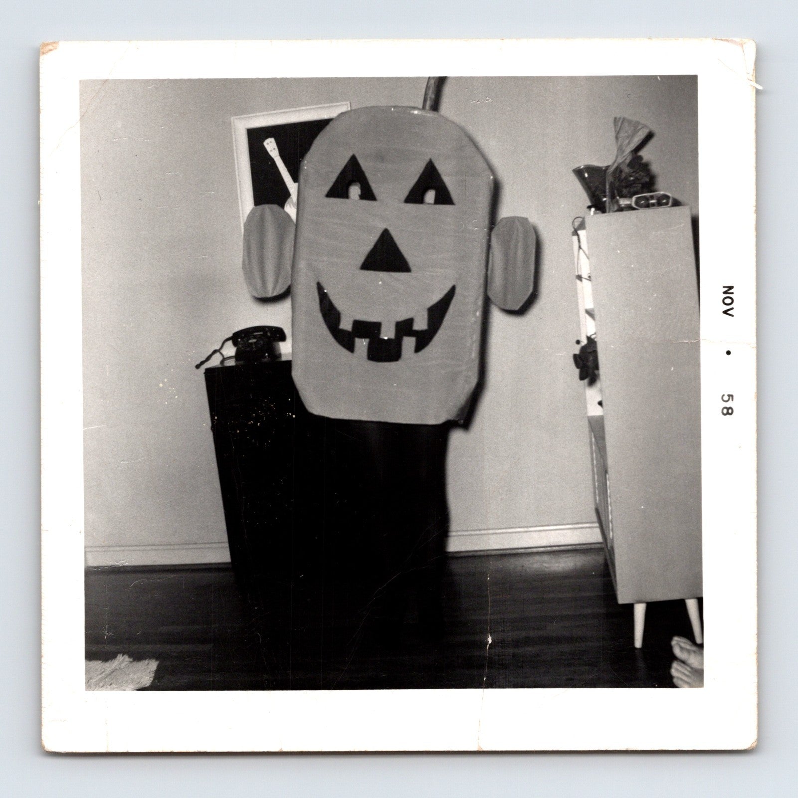 1958 Halloween pumpkin costume child hiding indoors snapshot square photo visible feet