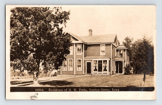 Garden Grove Iowa residence of H W Potts two story house with porch and trees, real photo postcard 1910s