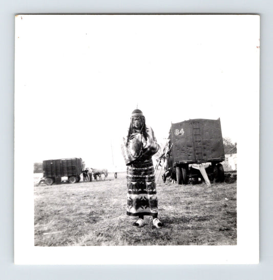 Clyde Beatty Circus performer in Native American costume standing near circus wagons, Concordia Kansas 1954