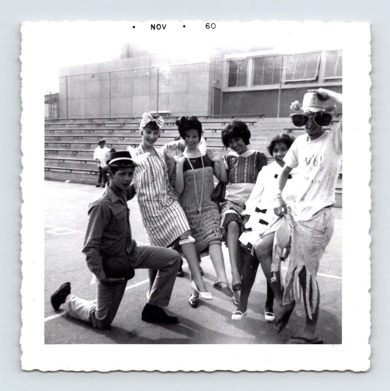 Halloween 1960 teenagers costumes posing outdoors bleachers novelty hats dresses group snapshot vintage photo