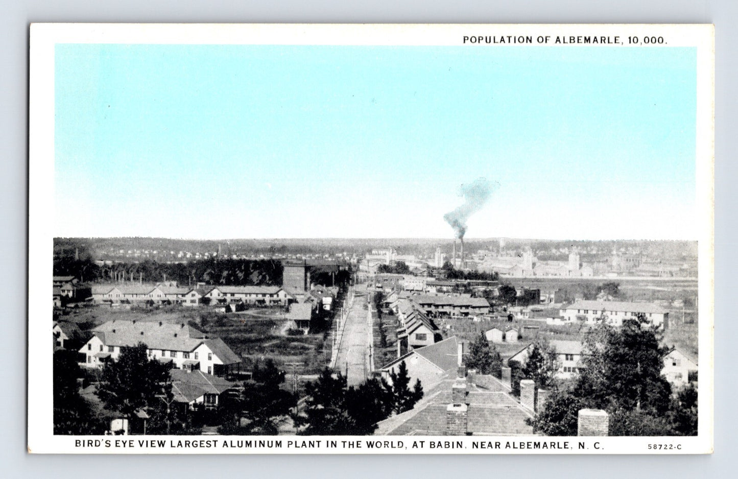 Bird’s-eye view of aluminum plant and townscape in Albemarle, North Carolina, with factory smoke plume in distance, 1930s.