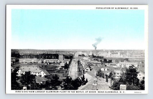 Bird’s-eye view of aluminum plant and townscape in Albemarle, North Carolina, with factory smoke plume in distance, 1930s.