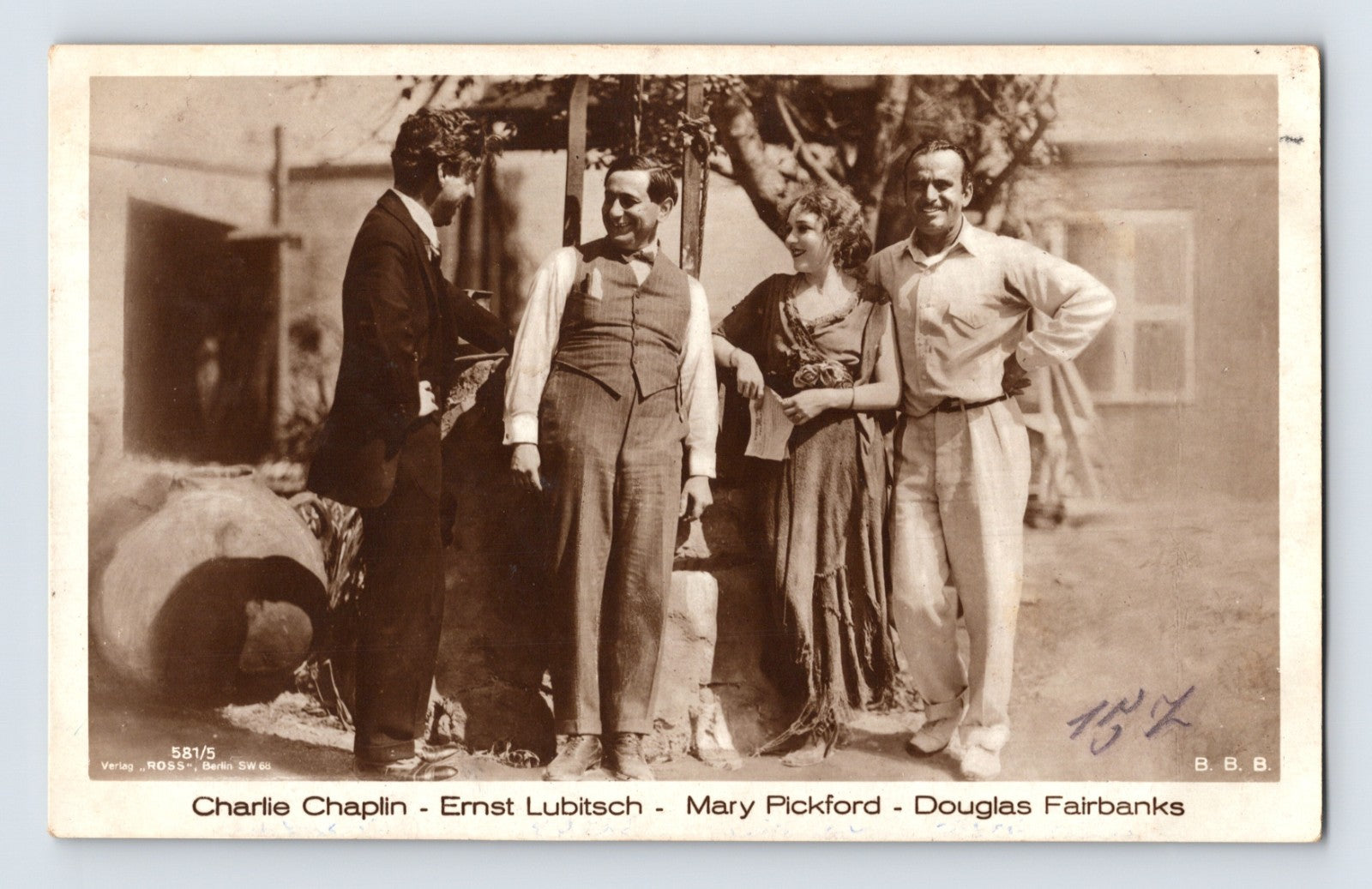 Real photo postcard of Charlie Chaplin, Ernst Lubitsch, Mary Pickford, and Douglas Fairbanks posed together outdoors, 1920s silent film era