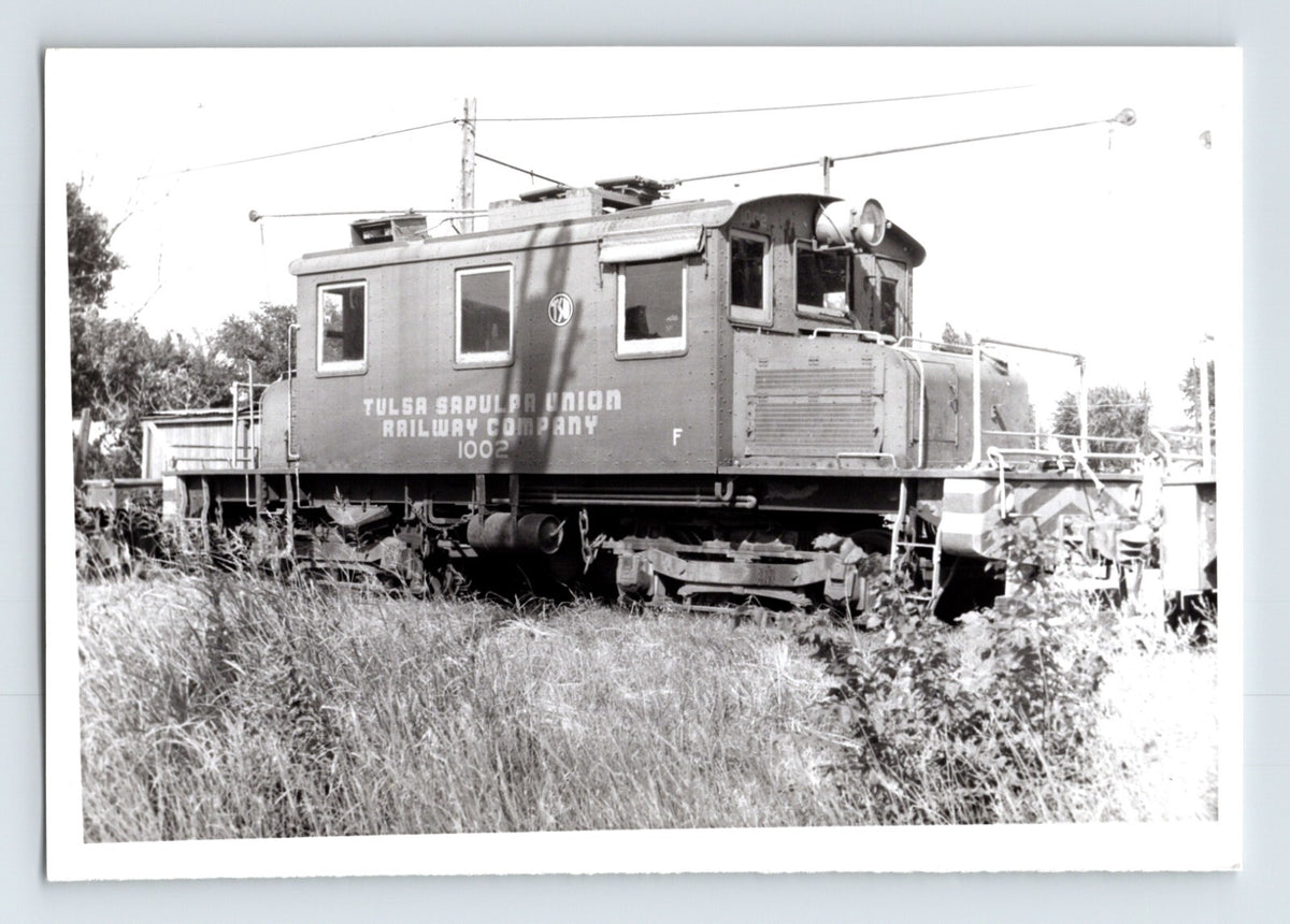 Tulsa Sapulpa Union Railroad electric switcher number 100 on track, side view of compact locomotive with overhead trolley equipment, 1960 black and white train photo