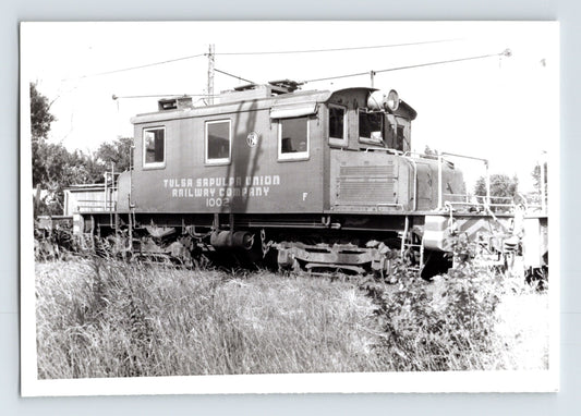 Tulsa Sapulpa Union Railroad electric switcher number 100 on track, side view of compact locomotive with overhead trolley equipment, 1960 black and white train photo