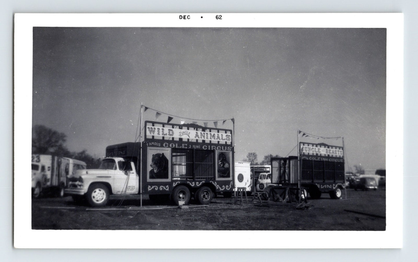 Cole Bros Circus black-and-white 1962 photograph showing jungle animal cage wagons and transport trucks on a circus lot.