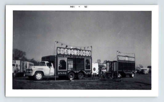 Cole Bros Circus black-and-white 1962 photograph showing jungle animal cage wagons and transport trucks on a circus lot.