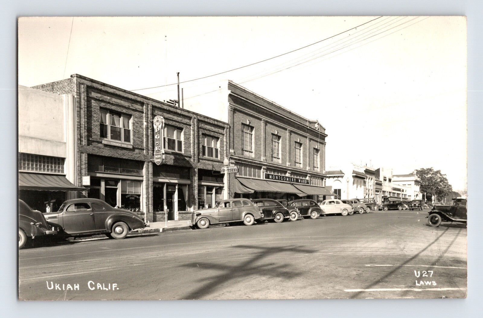 Ukiah California downtown street scene showing PG and E building, Montgomery Ward storefront, and rows of 1940s automobiles parked along wide main street