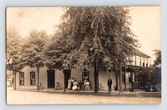 Vintage sepia-toned photograph of a group of people standing outside a building with trees in the foreground.