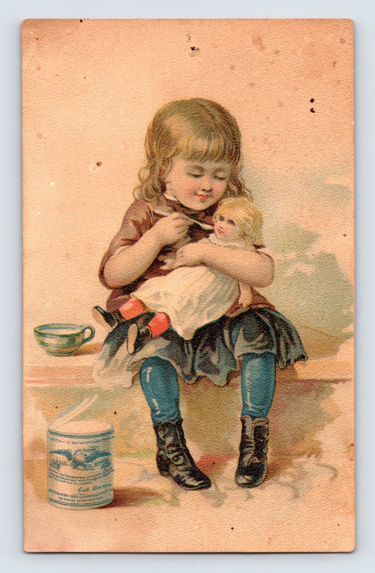 Gail Borden Eagle Brand Condensed Milk Victorian trade card featuring a young girl feeding a doll beside a can of condensed milk.