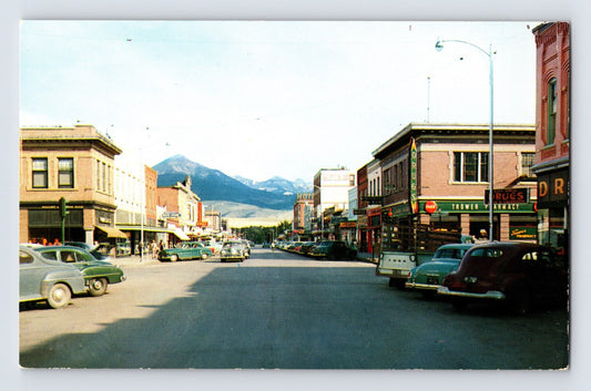 Livingston Montana downtown street view with vintage cars storefronts Coca Cola sign mountain backdrop 1960s postcard