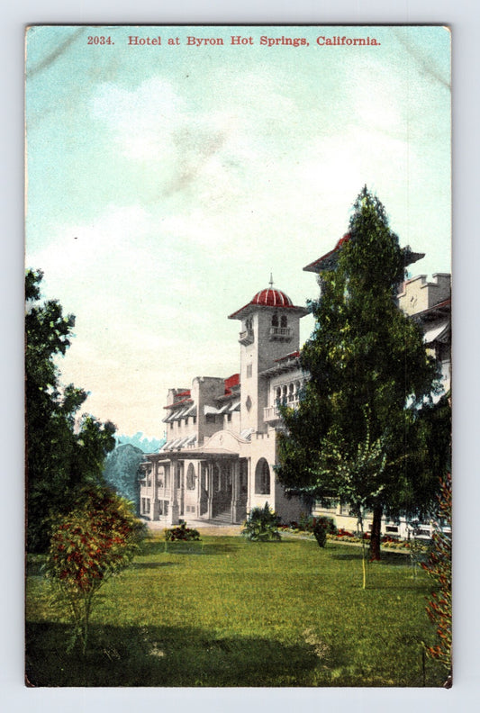 Mediterranean style hotel building at Byron Hot Springs resort in California with red tiled tower and landscaped lawn, early 1900s postcard view