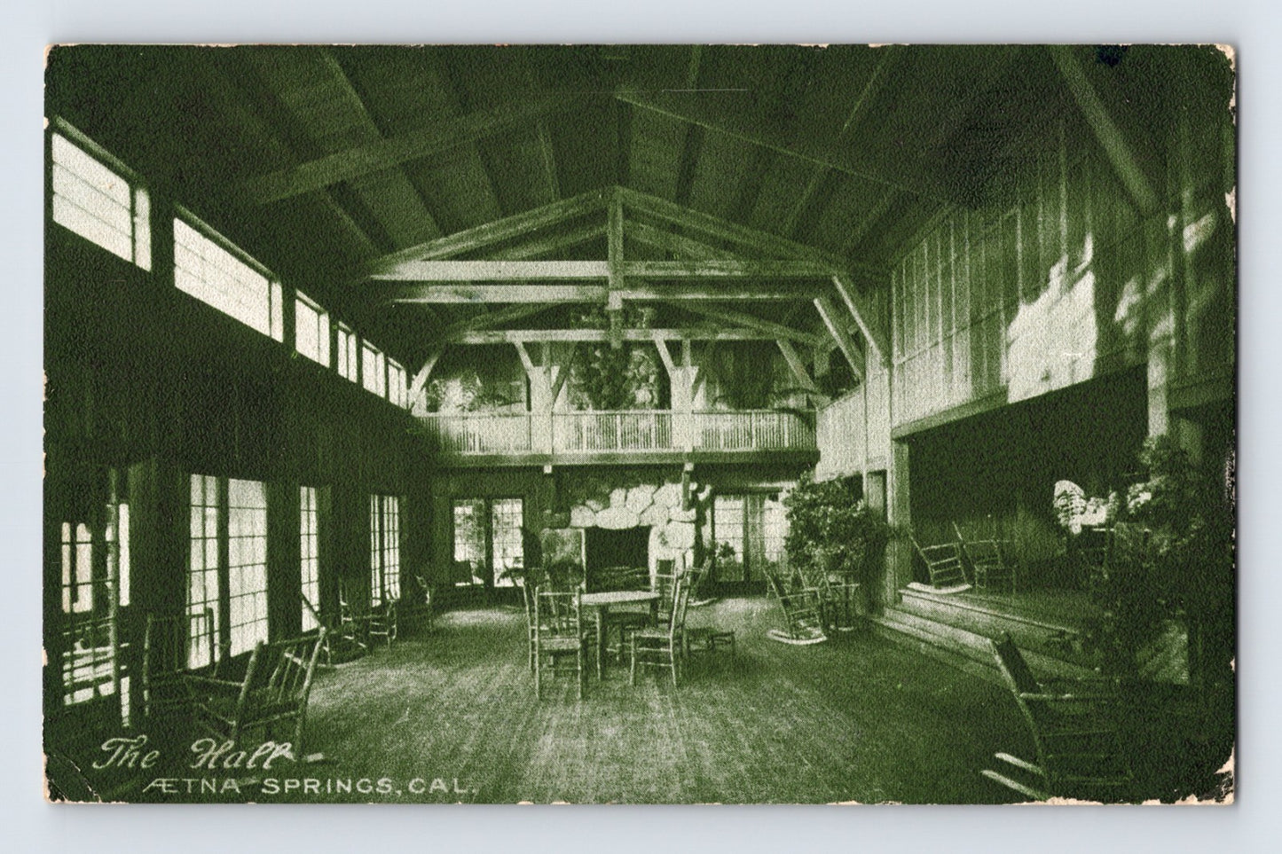 Aetna Springs California resort hall postcard showing rustic lodge interior with exposed beams, rocking chairs, fireplace, and open gathering space.