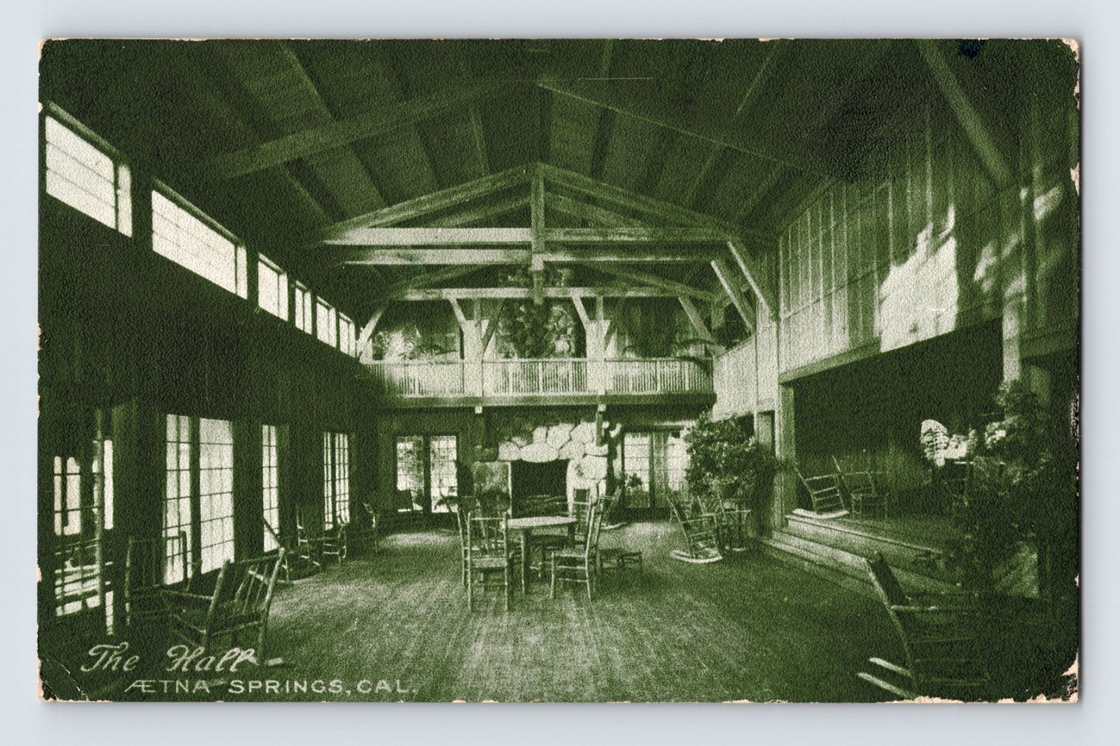 Aetna Springs California resort hall postcard showing rustic lodge interior with exposed beams, rocking chairs, fireplace, and open gathering space.