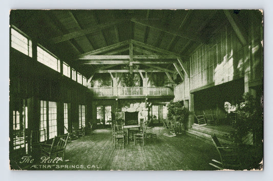 Aetna Springs California resort hall postcard showing rustic lodge interior with exposed beams, rocking chairs, fireplace, and open gathering space.