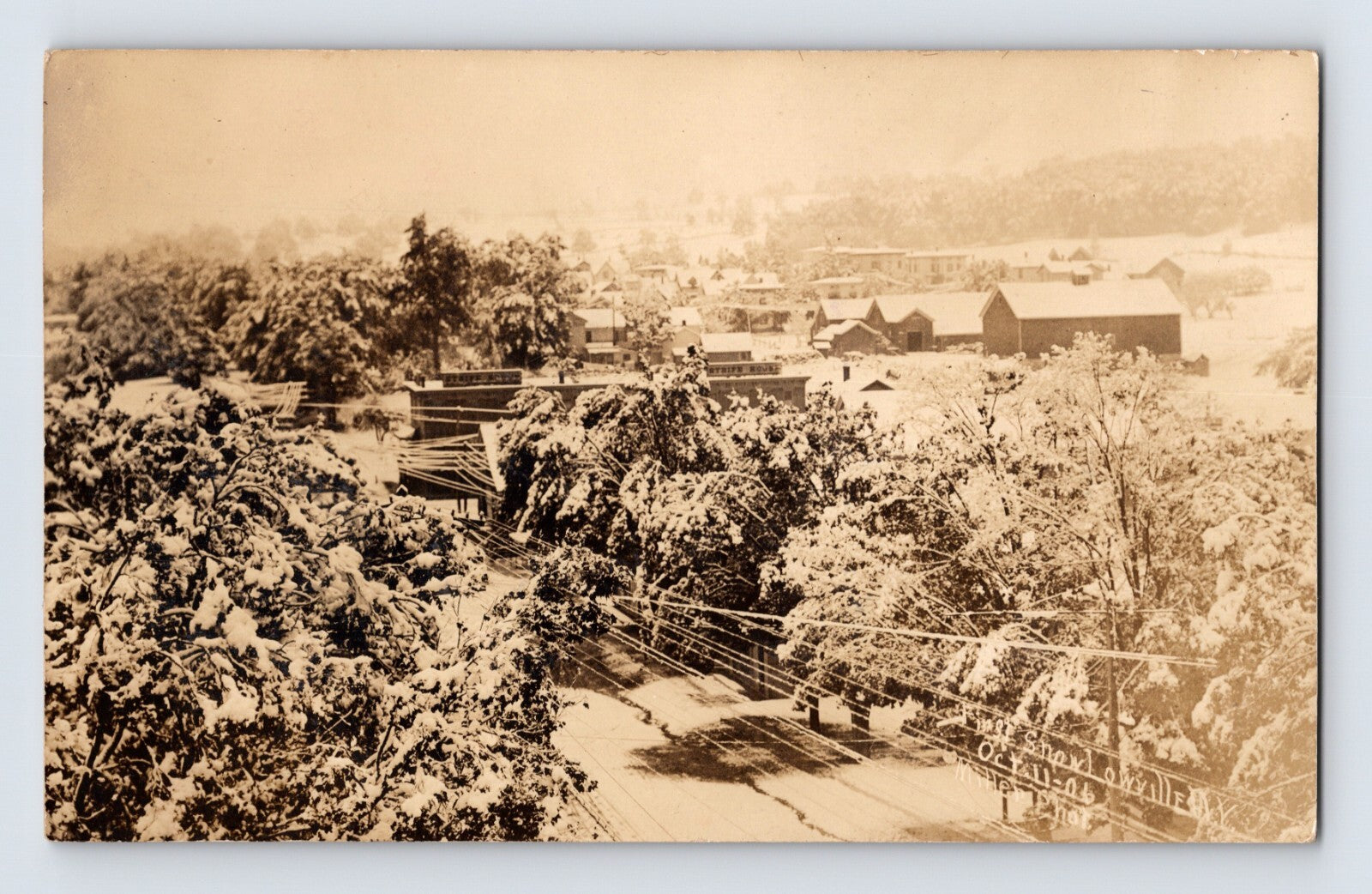 Real photo postcard view of downtown Lowville New York covered in early snowfall 1911 with rooftops and trees blanketed in snow