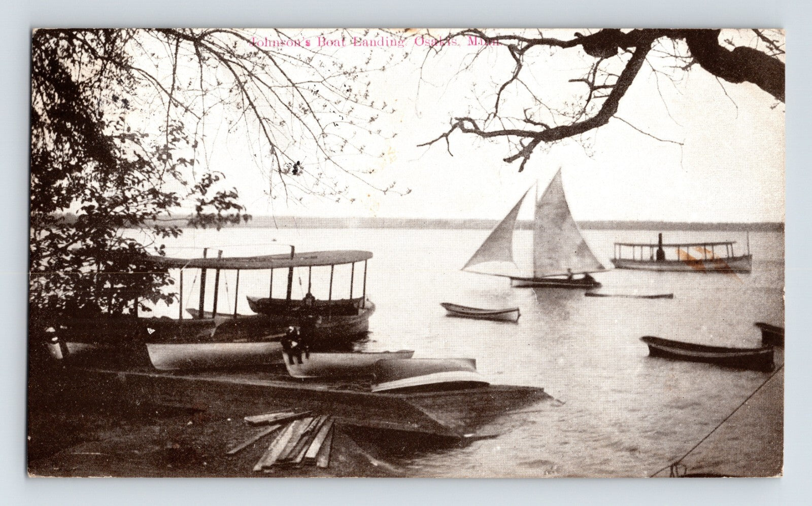 Johnson’s Boat Landing on Lake Osakis Minnesota showing sailboat, rowboats, canoes, and early motor launches along wooded shoreline