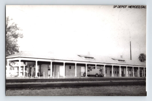 Postcard front showing the Southern Pacific Railroad depot at Merced, California, with long colonnaded platform and mid-century vehicle; real photo postcard, 1950s.