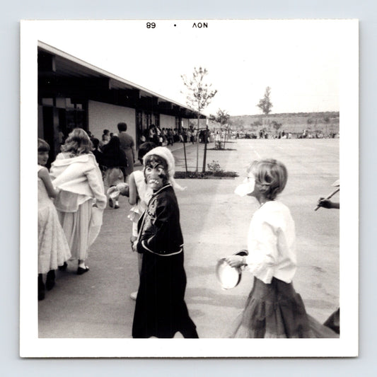 Halloween school parade child mask turning toward camera playground line costumes 1960s snapshot 3.5 x 3.5 photo