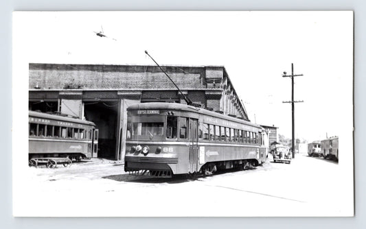 Philadelphia Suburban Transportation Company trolley car 86 at 69th Street Terminal, 1951, black and white photo with brick car barn and adjacent streetcars visible
