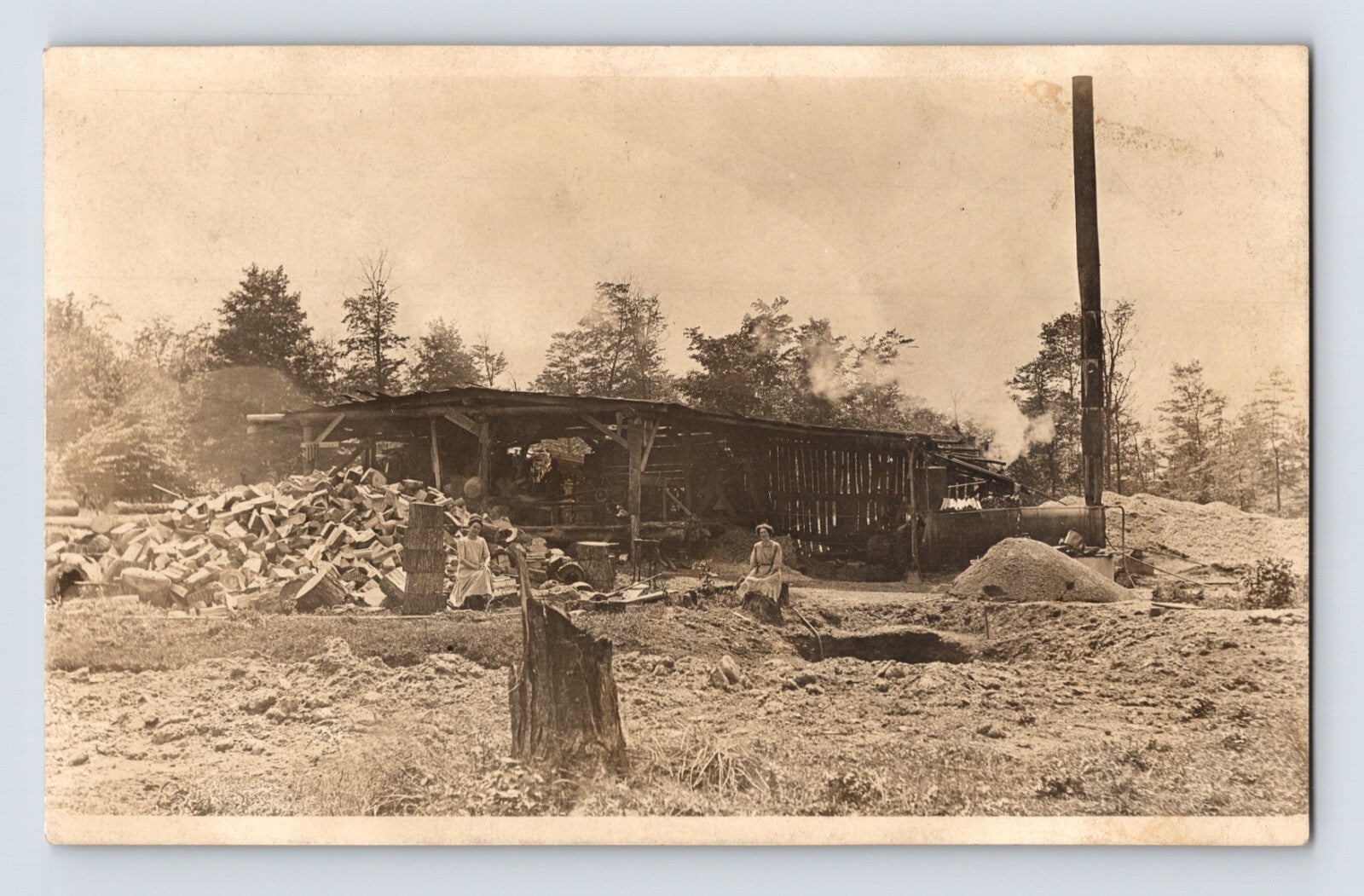 Vintage sepia-toned photograph of a cabin in a forest with people around.