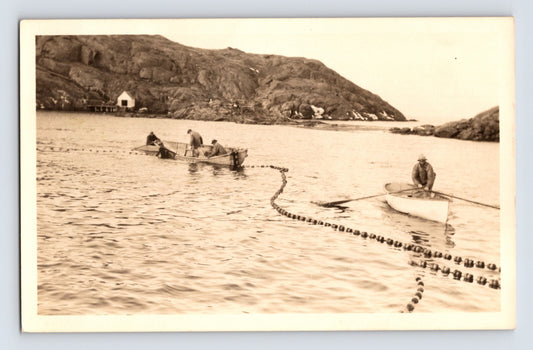 Monhegan Maine fishermen seining with rowboats and net floats in rocky harbor RPPC 1940s