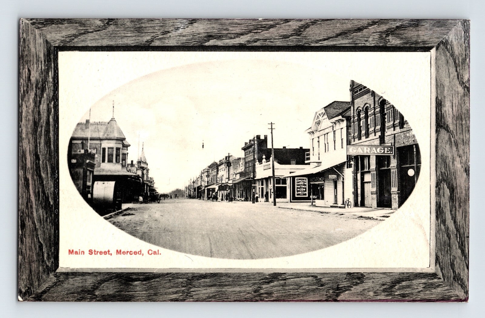 Main Street downtown Merced California with early storefronts and streetcar tracks oval view postcard