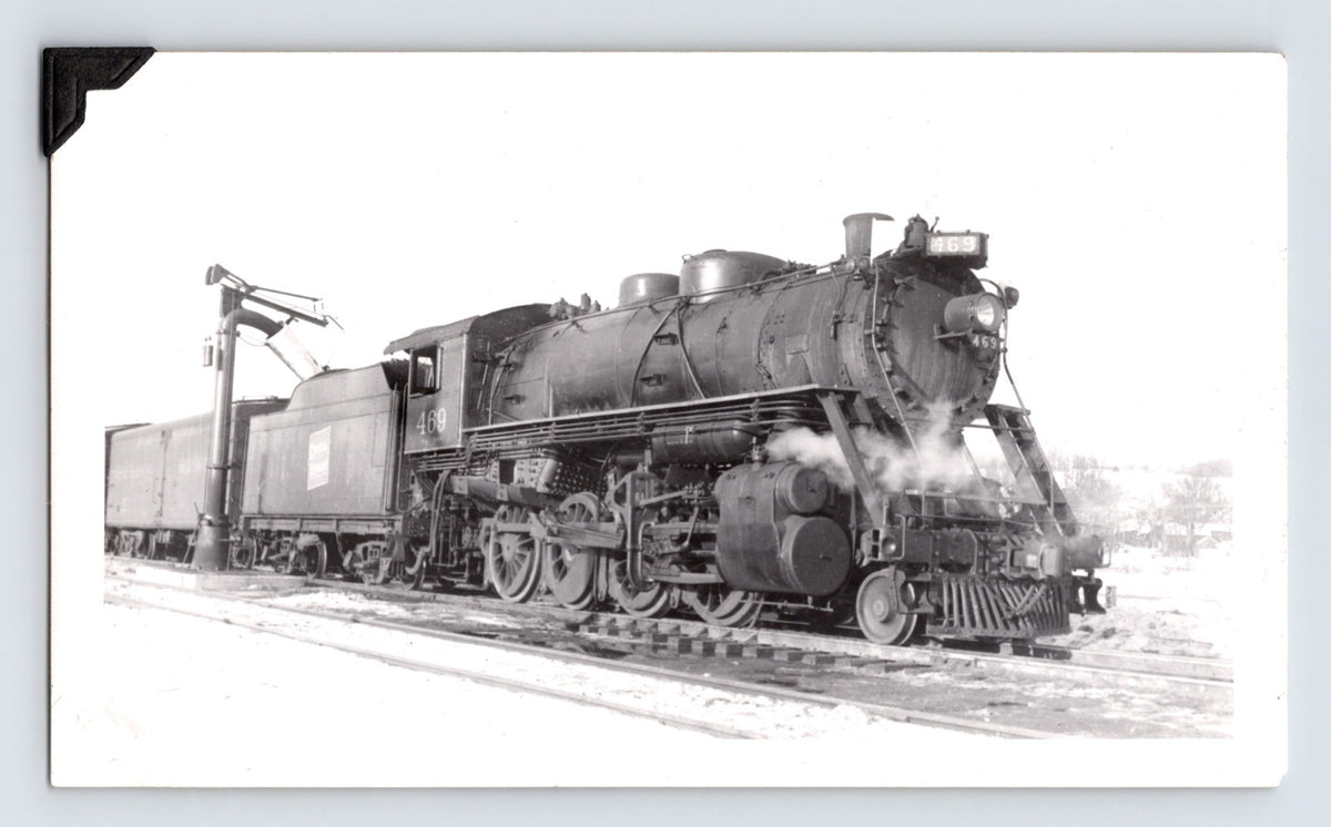 Black and white photograph showing Central Vermont Railroad 2-8-0 steam locomotive at Montpelier, Vermont in 1948 with tender and trackside water crane visible