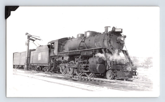 Black and white photograph showing Central Vermont Railroad 2-8-0 steam locomotive at Montpelier, Vermont in 1948 with tender and trackside water crane visible