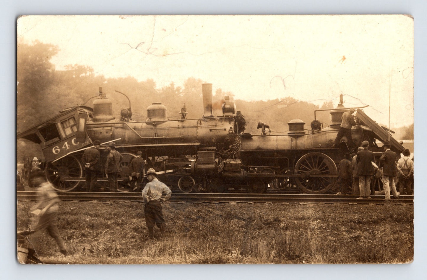 Real photo postcard showing head-on steam locomotive collision with crew and onlookers standing beside damaged engines, circa 1910s