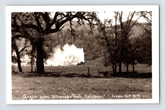 Calistoga California geyser real photo postcard viewed from Silverado Trail with erupting steam plume framed by oak trees and Napa Valley hills.