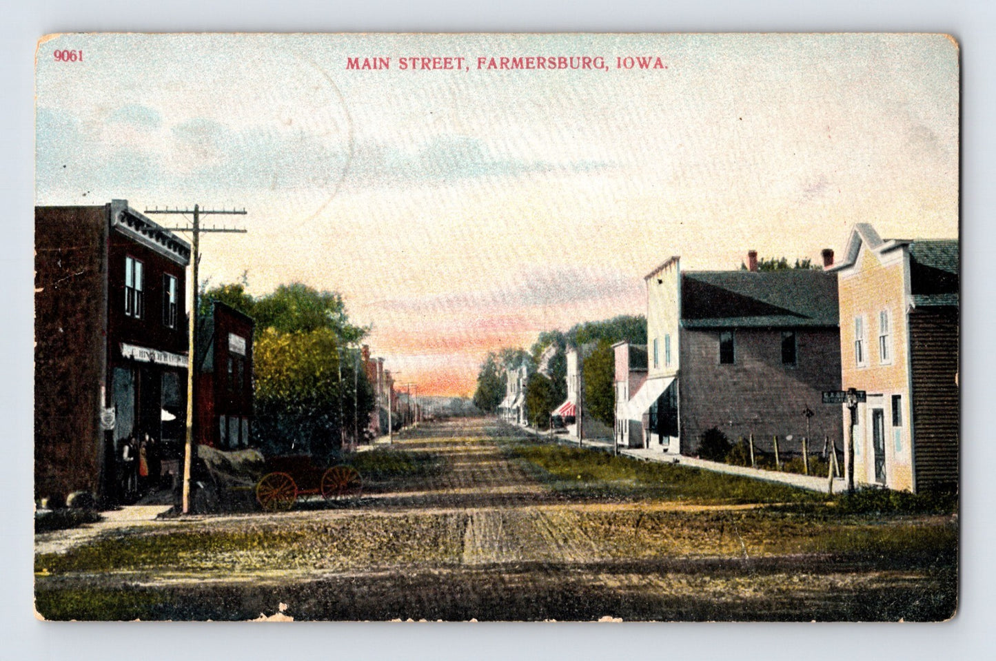 Colorized streetscape view of Main Street with storefronts and dirt road in Farmersburg Iowa 1909 postcard