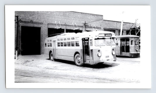 Chicago Transit Authority trolley coach 3017 at DeKalb Shops carhouse with overhead wires and brick garage bay, mid-century black and white transit photograph