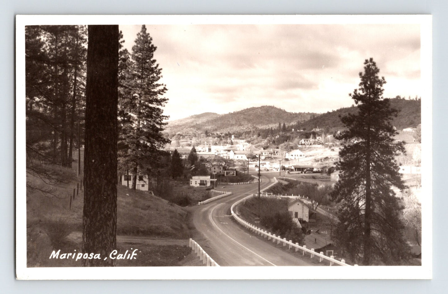 1950s Mariposa California Southern Entrance Road curving highway view with pine trees hillside homes and Sierra foothills