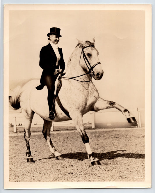 Vintage photograph of a person riding a horse in an equestrian setting