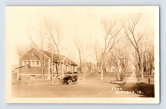 Audubon Iowa residential street with early automobile and park setting 1930s real photo postcard