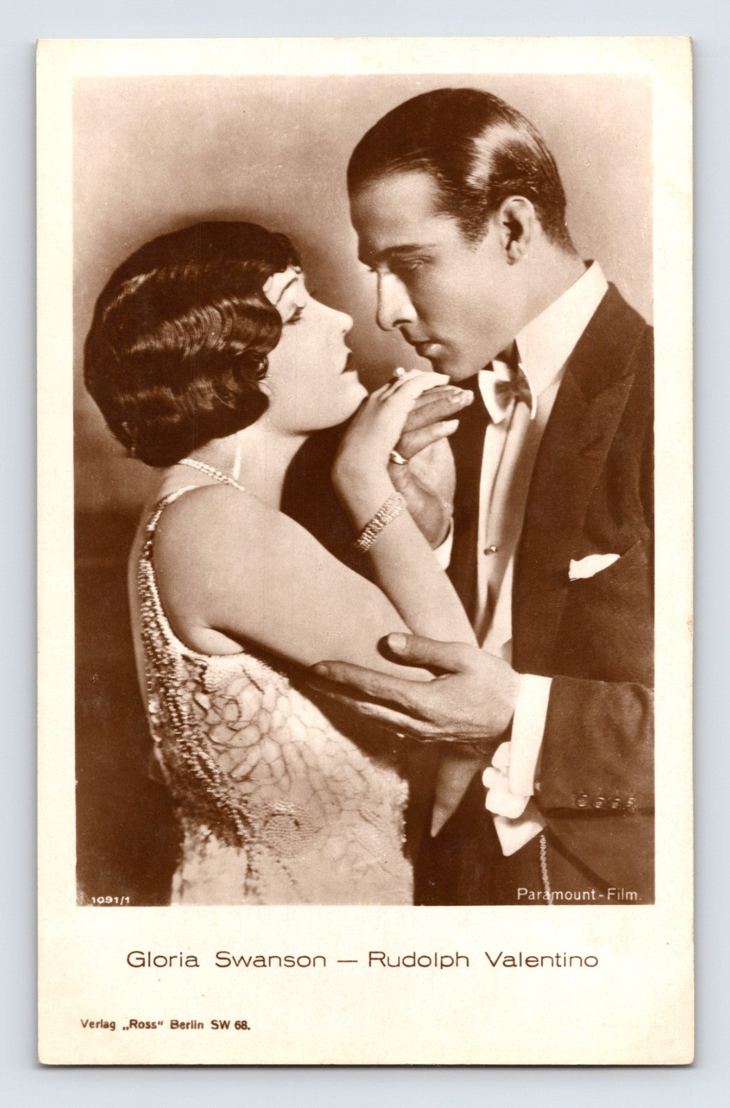 Sepia real photo postcard of Gloria Swanson and Rudolph Valentino in close embrace from Paramount film publicity portrait