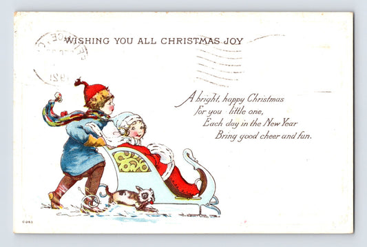 Christmas postcard showing a bundled child pushing Santa Claus in a sled beside a small dog, with embossed holiday verse and 1921 Detroit Michigan postmark.