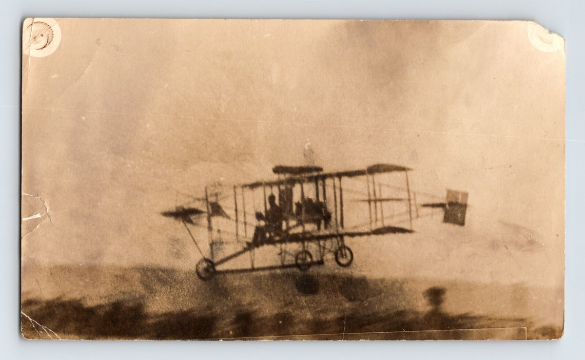 Early Curtiss pusher biplane in flight with tricycle landing gear and exposed framework over open landscape circa 1910s