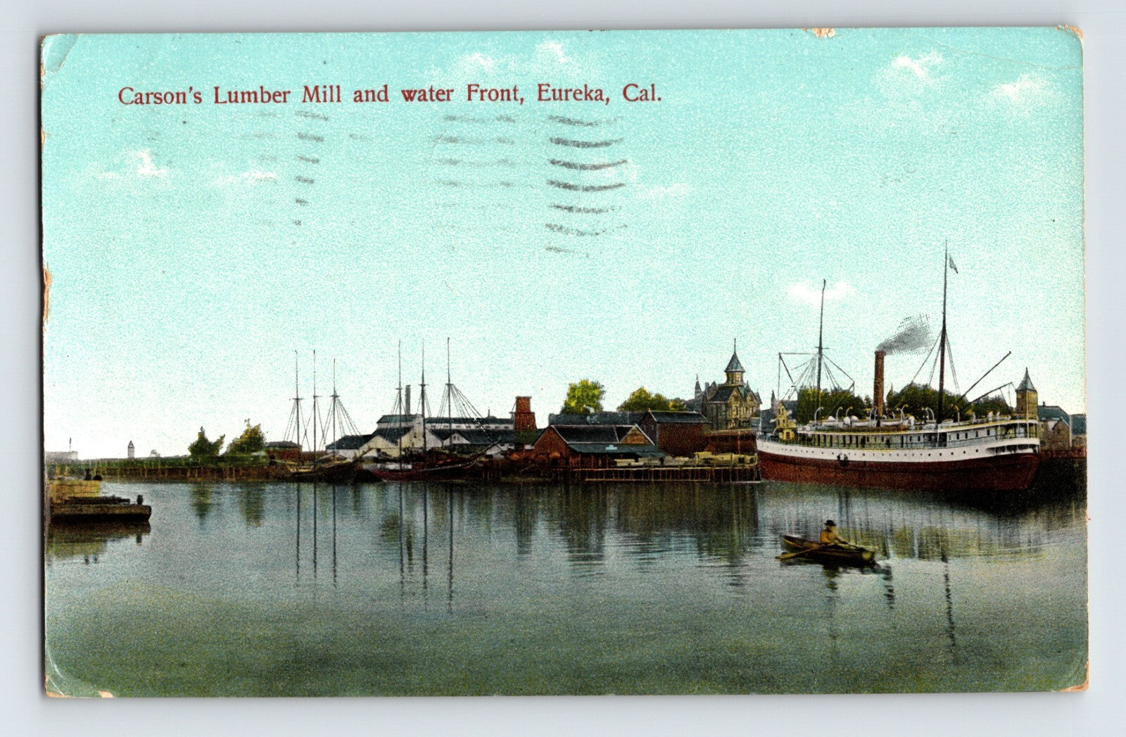 Harbor view of Carson’s Lumber Mill and waterfront in Eureka, California, showing steamship at dock, lumber stacks, small rowboat in foreground, and calm water reflections.