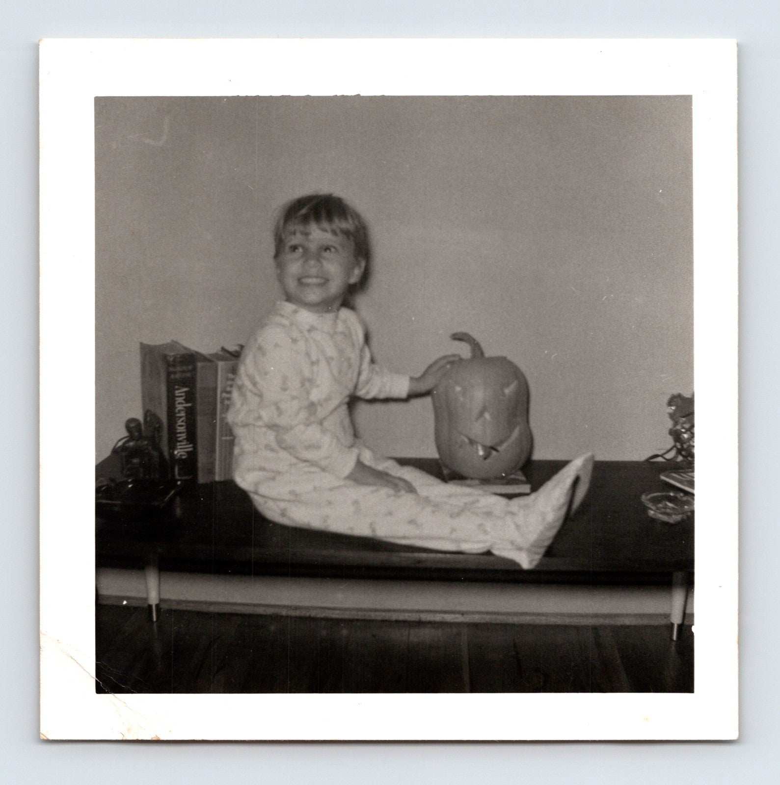 Vintage Halloween snapshot child sitting table jack o lantern pajamas 1950s square photo