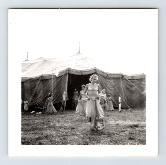 Vintage black and white photo of a woman walking in front of circus tents.