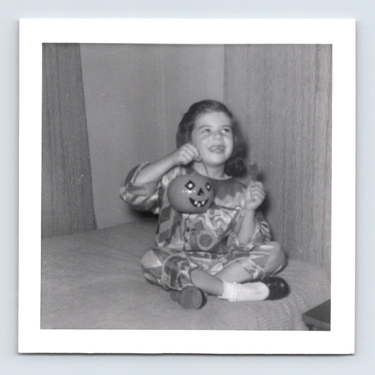 Vintage Halloween girl costume pumpkin bucket sitting on couch 1957 snapshot black white photo